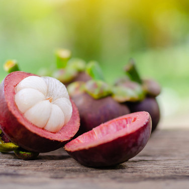 a perfectly cut mangosteen fruit laid open with flesh in view on a wooden table