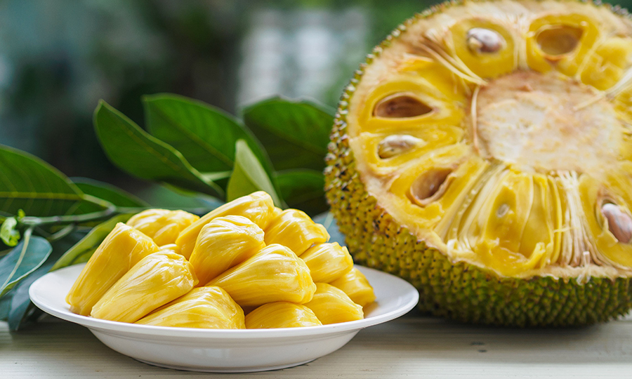 half sliced jackfruit with flesh out and plate of jackfruit