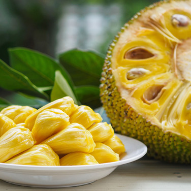 half sliced jackfruit with flesh out and plate of jackfruit