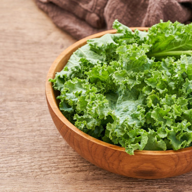 small wooden bowl of kale on wooden table