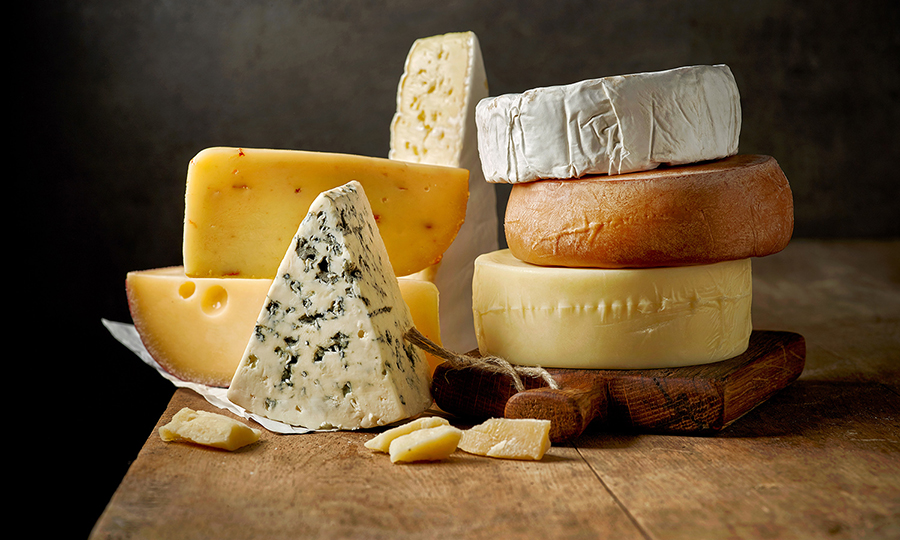 A wide variety of cheeses on a wooden surface