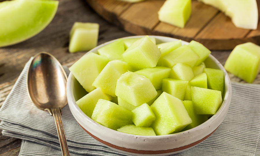 sliced open honeydew on wooden cutting board