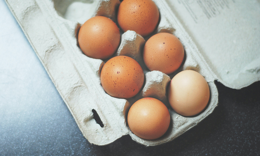 Half a dozen brown eggs in an egg carton container