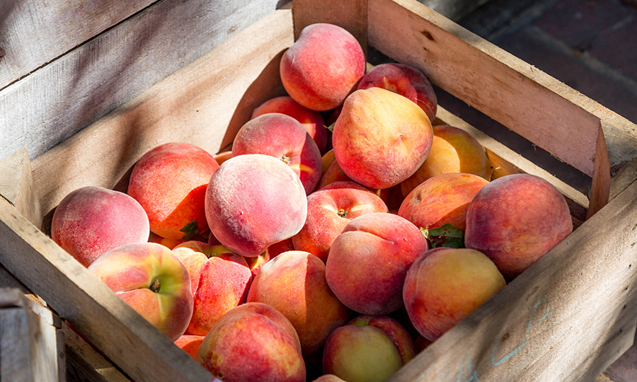 a wooden crate full of ripe peaches