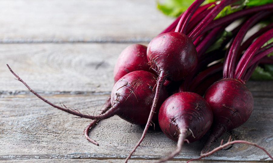 ripe clean beets scattered on wooden surface