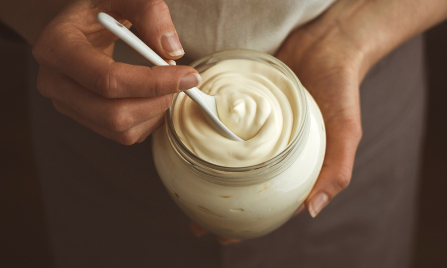woman scooping a small spoonful of mayonnaise