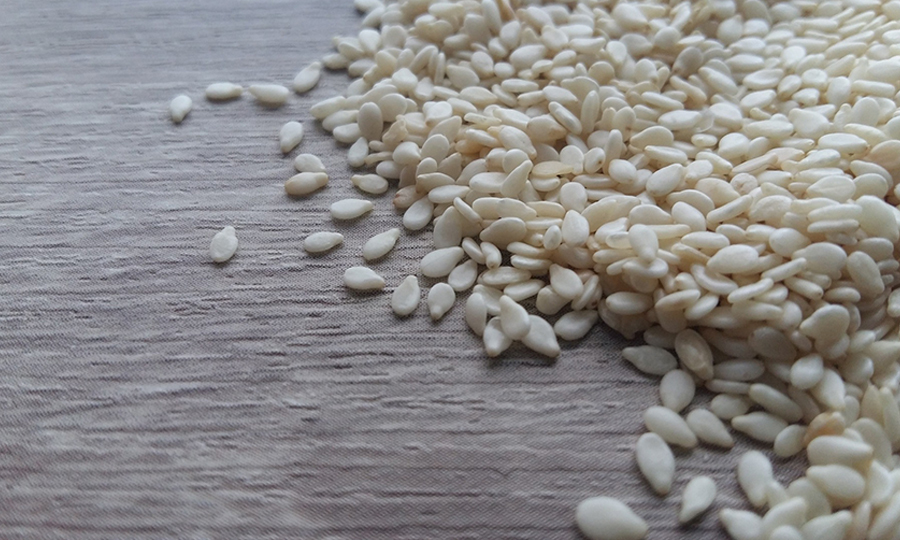 pile of sesame seeds on wooden surface