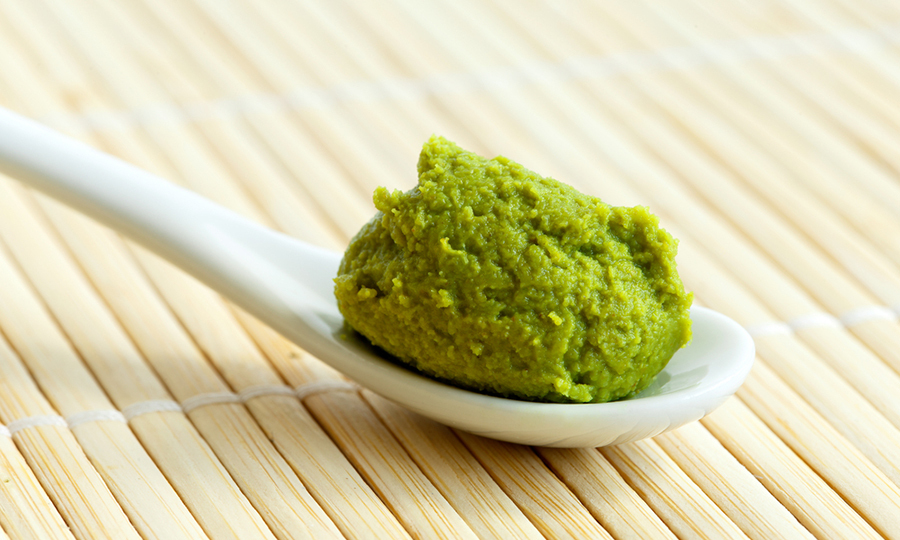 a spoonful of wasabi paste on bamboo mat