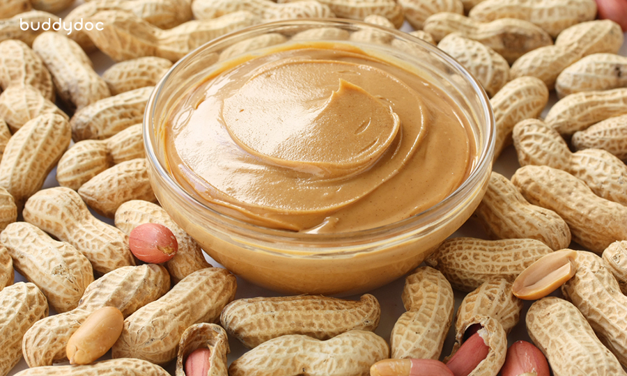 close up of glass bowl of peanut butter surrounded by peanut shells