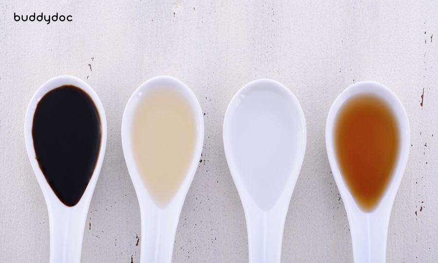 four white soup spoons filled with four different types of vinegar