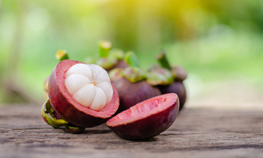 a perfectly cut mangosteen fruit laid open with flesh in view on a wooden table